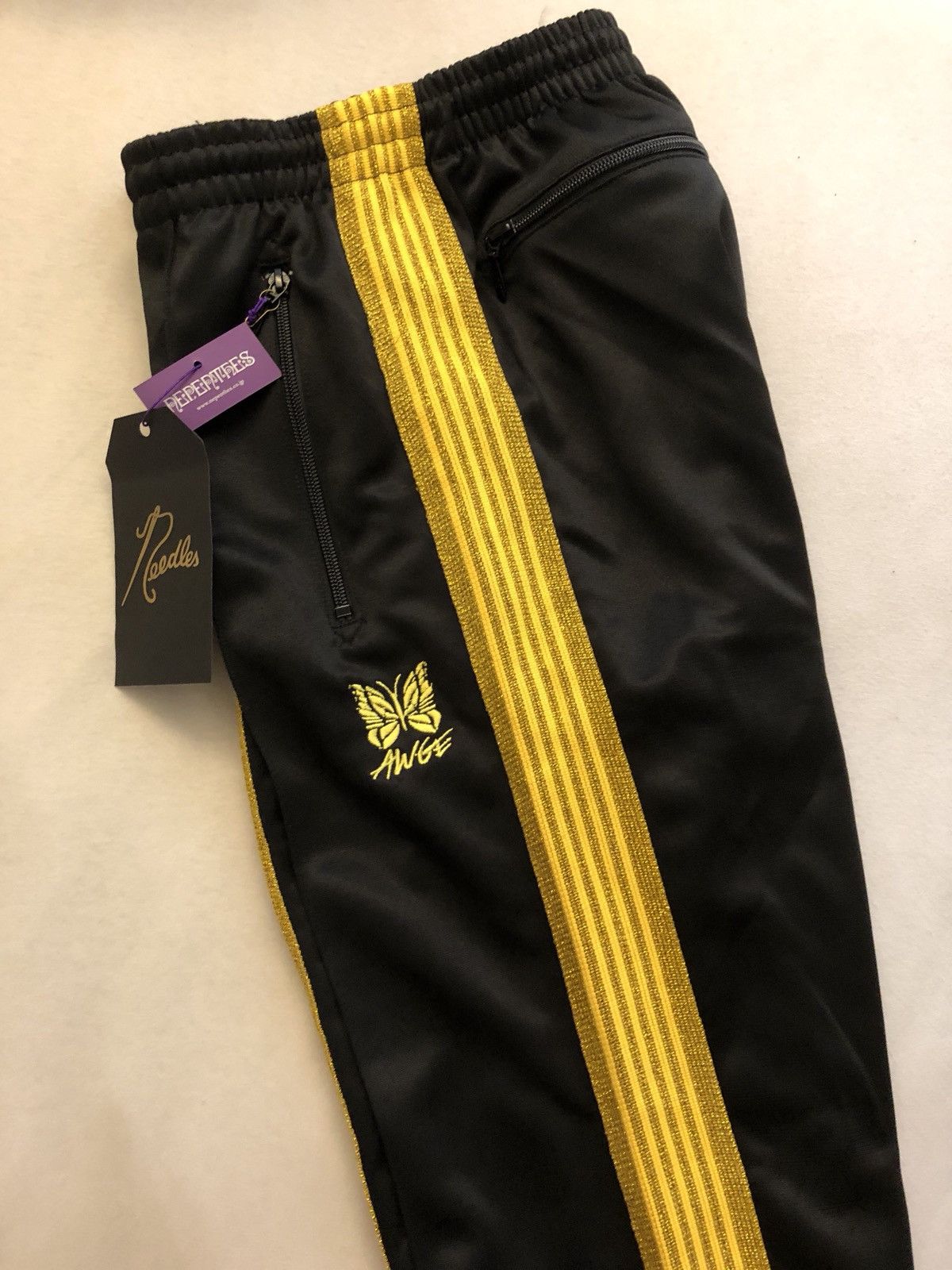 AWGE × Needles AWGE x NEEDLES track pants in black//gold | Grailed