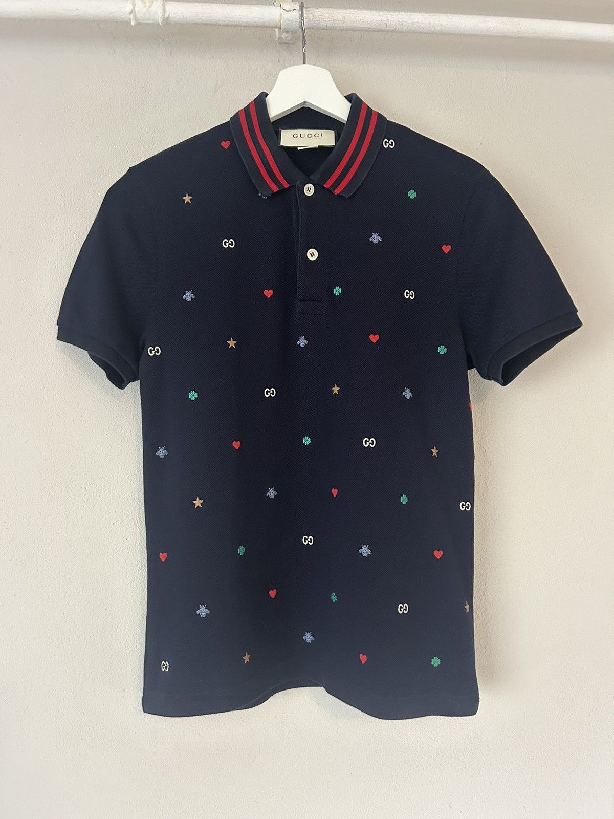 Navy polo with embroidered motifs and red striped collar