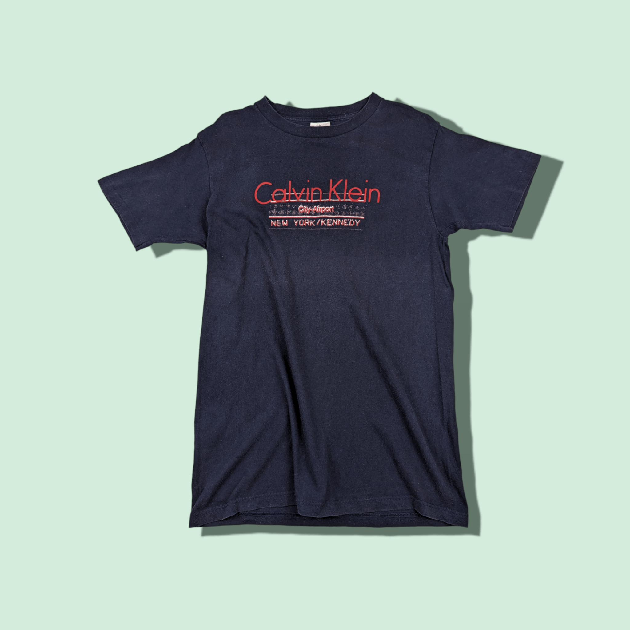 image of VTG Calvin Klein Jf Kennedy Airport T-Shirt Single Stitches in Indigo, Men's (Size Medium)