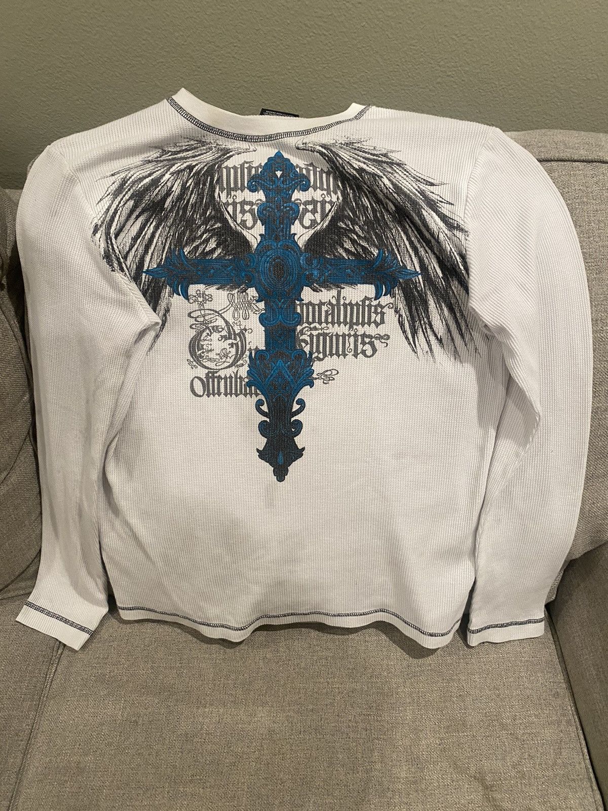 a light beige long-sleeved shirt with a blue cross on it